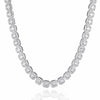 A silver-toned tennis necklace paved with round and cushion-cut clear stones, displayed on a clean white background with a subtle reflection below.