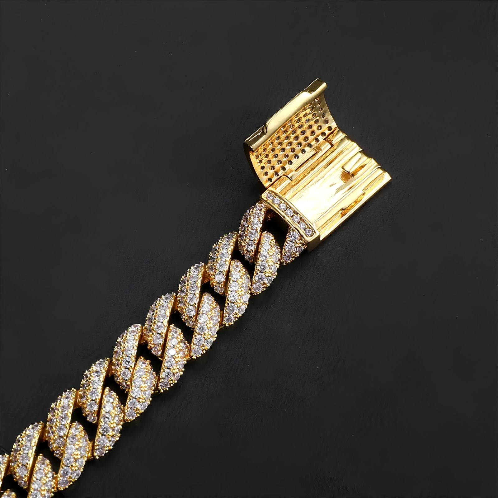A close-up of a gold-tone Cuban link chain bracelet paved with small clear stones, shown against a dark black background.
