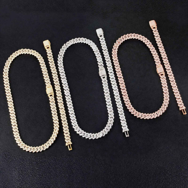 Four Cuban link chain necklaces in gold, silver, and rose gold tones, arranged side-by-side on a black textured background.