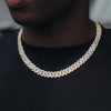 A close-up of a person wearing a 10mm gold-toned cuban chain necklace paved with small clear stones, styled over a black t-shirt.