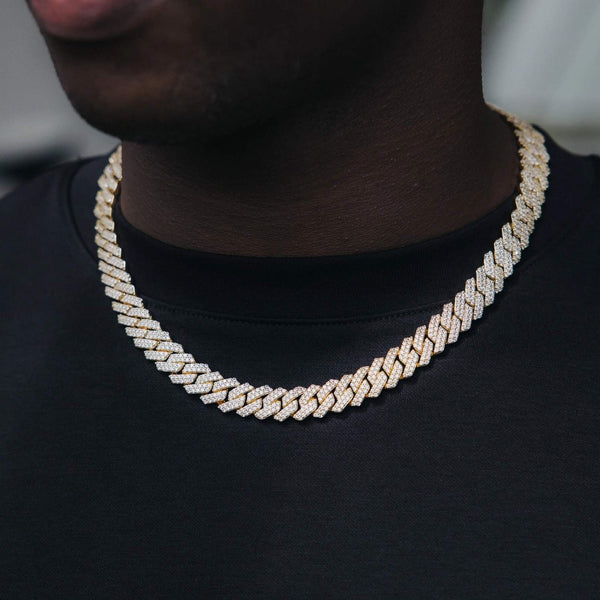 A close-up of a person wearing a 10mm gold-toned cuban chain necklace paved with small clear stones, styled over a black t-shirt.
