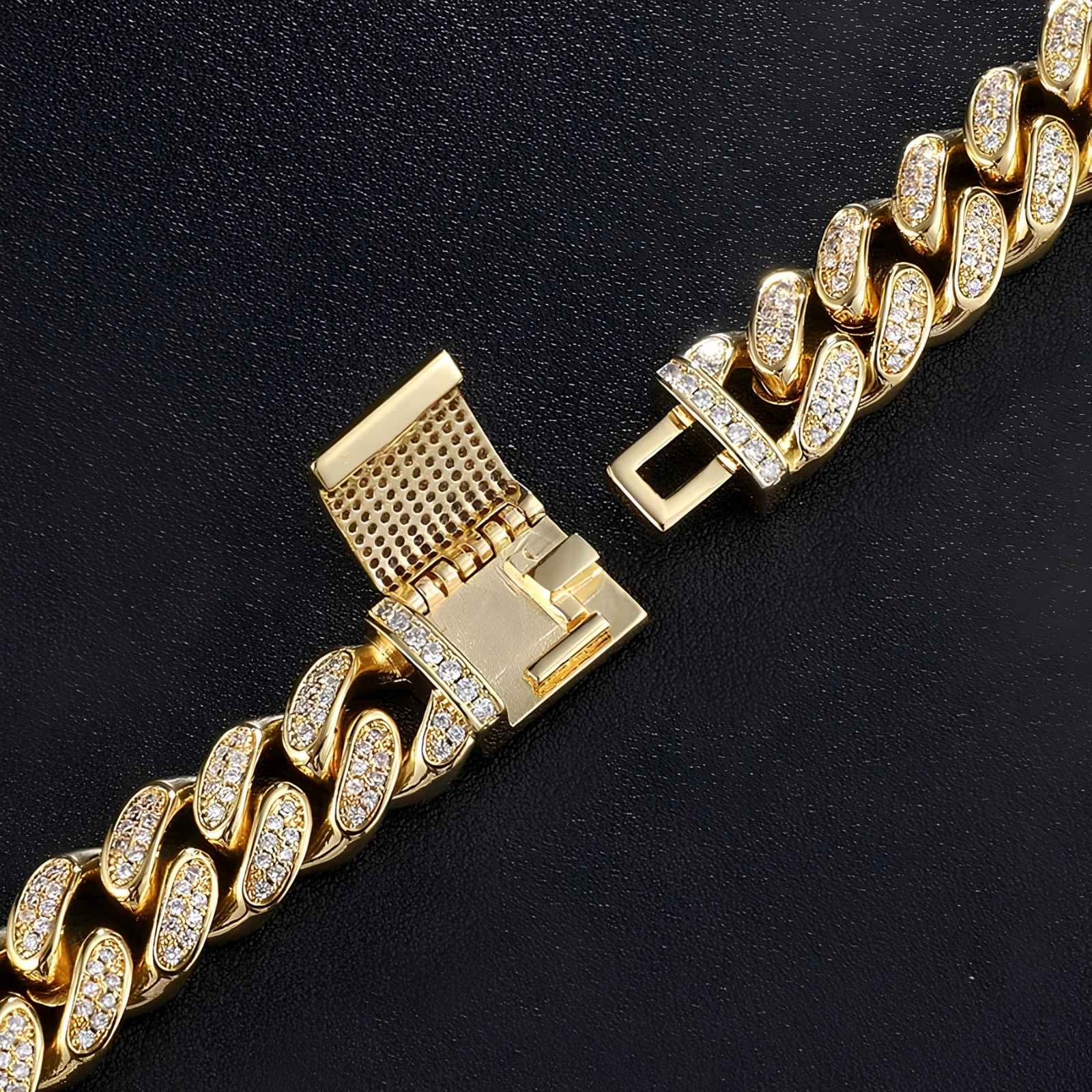 A gold-toned Cuban link chain with pavé-set clear stones, shown in close-up on a dark textured background. The clasp is visible