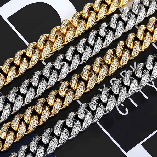 Four Cuban links in gold, silver, and two-tone finishes, each paved with small clear stones, arranged diagonally on a black and white graphic background.