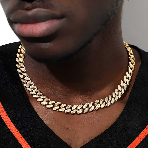 Gold cuban chain worn by a person with a neutral background