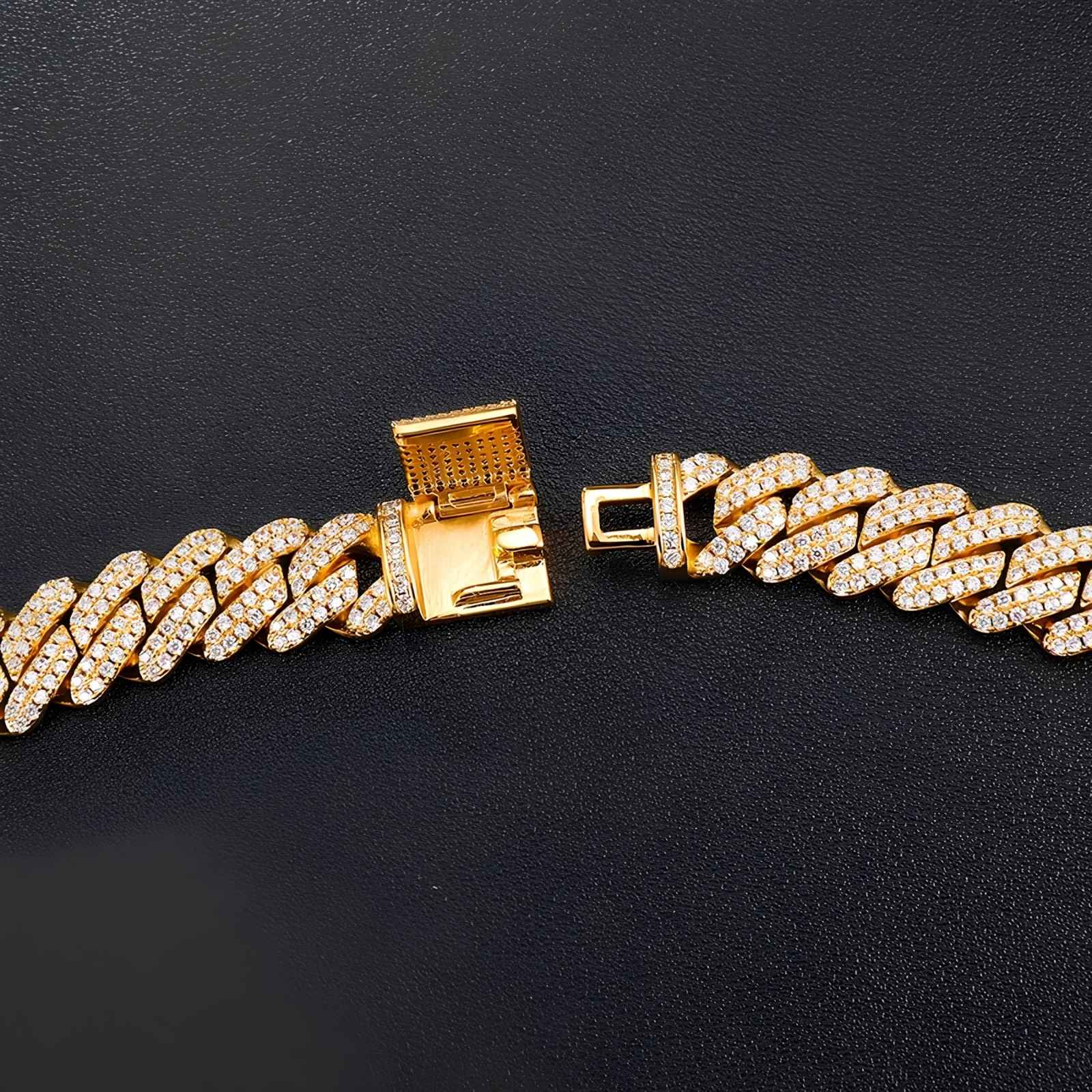 A gold-tone Cuban link bracelet paved with small clear stones, shown on a dark textured background. The clasp is open to display the interior mechanism.