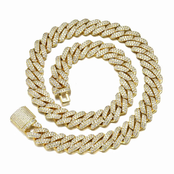 A thick gold Cuban link chain necklace, heavily embellished with small clear stones, coiled on a plain white background.