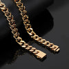 A close-up of a thick gold Cuban link chain necklace draped over a black display stand on a glossy black surface.