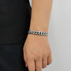 Silver cuban bracelet on a wrist against a plain background