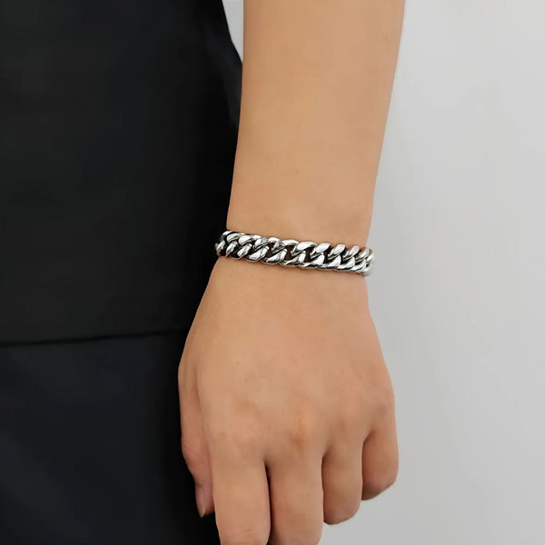 Silver cuban bracelet on a wrist against a plain background