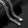 A close-up of a shiny silver Cuban link chain draped over a black cylindrical display stand on a dark reflective surface.