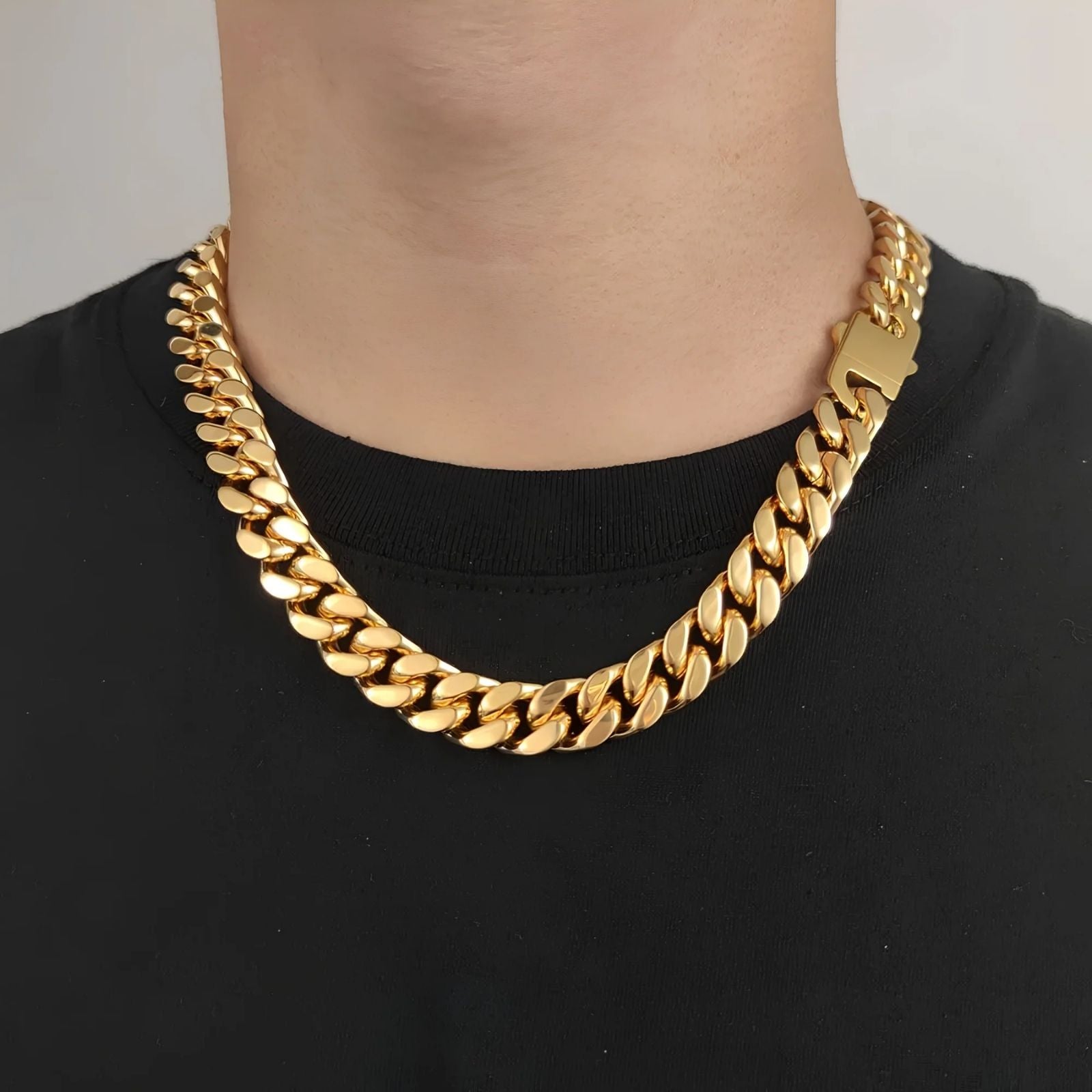 A close-up of a person wearing a thick, shiny gold Cuban link chain necklace over a black t-shirt.