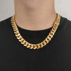 A close-up of a person wearing a thick, shiny gold Cuban link chain necklace over a black t-shirt.