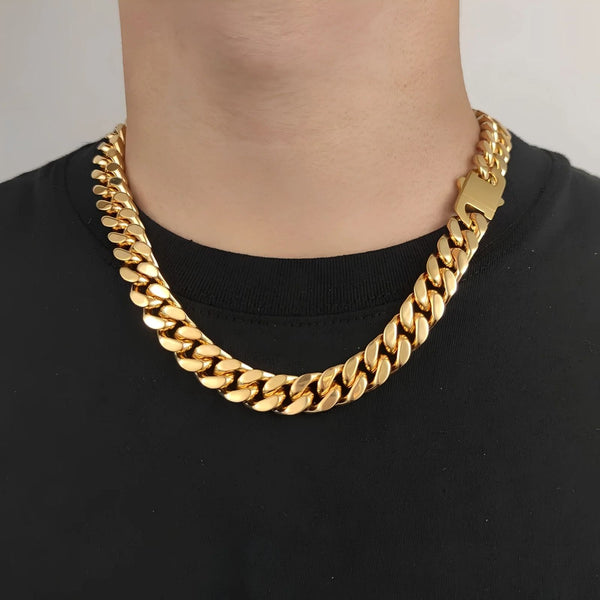 A close-up of a person wearing a thick, shiny gold Cuban link chain necklace over a black t-shirt.