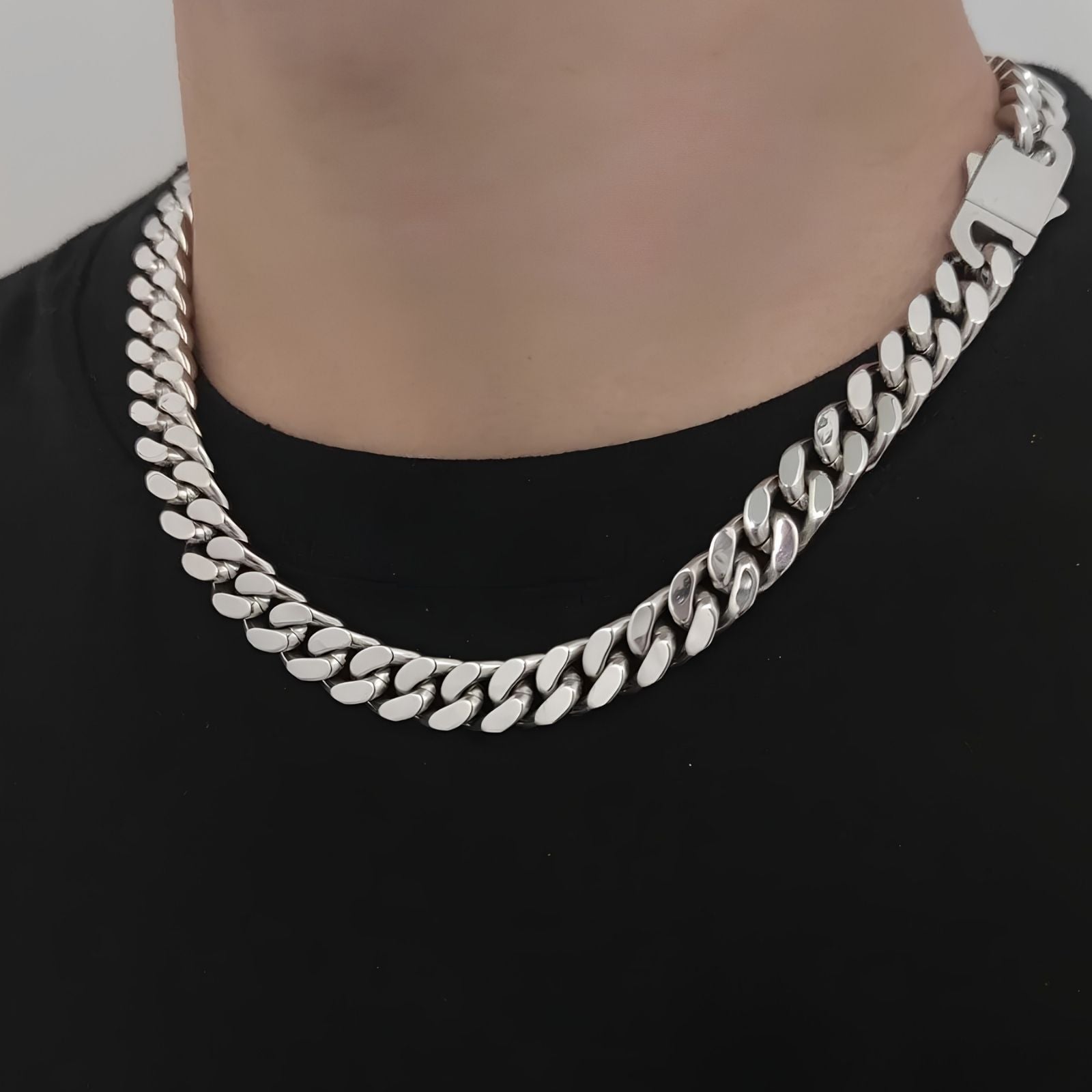 Silver chain necklace worn by a person on a black background