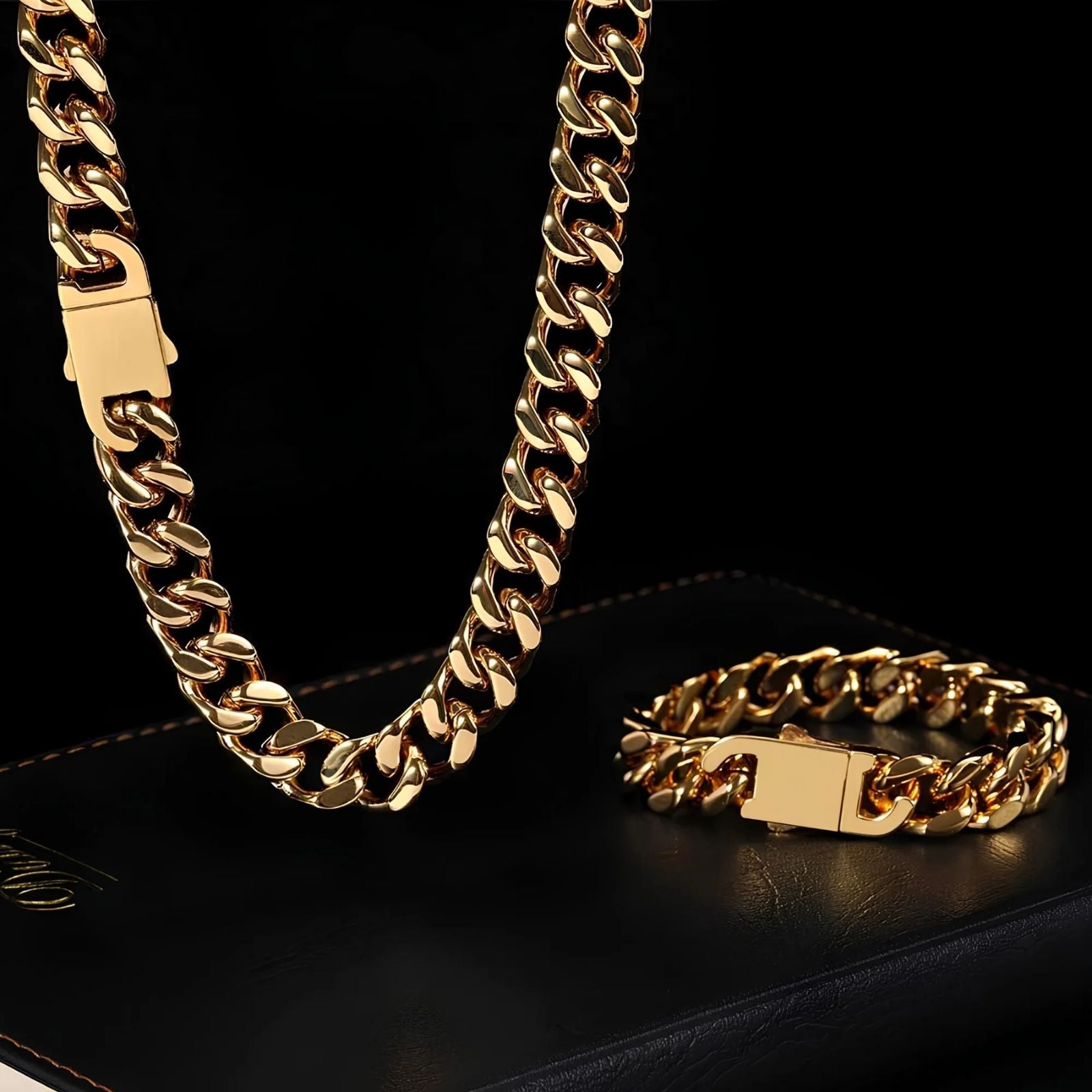 A gold-tone Cuban link chain necklace and matching bracelet displayed on a black surface against a black background.