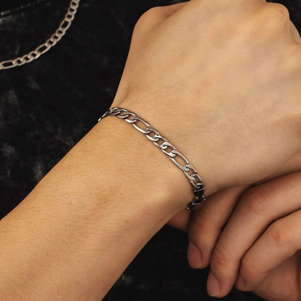 Silver chain bracelet on a wrist against a dark background