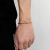 Gold bracelet on a wrist against a neutral background
