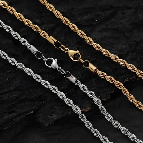 Two rope chains, one gold and one silver, on a dark textured surface.