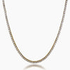 A gold tennis necklace paved with small clear cubic zirconia stones, shown in a curved U-shape against a light gray background.