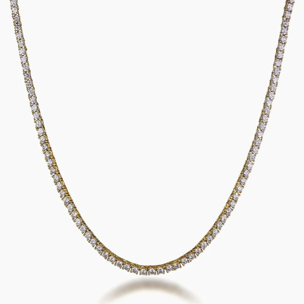A gold tennis necklace paved with small clear cubic zirconia stones, shown in a curved U-shape against a light gray background.