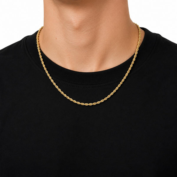 A close-up of a person's neck and upper chest wearing a gold rope chain necklace over a black crewneck t-shirt, against a plain white background.