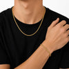 A close-up of a person wearing a gold chain necklace and a matching gold bracelet, with the person wearing a black t-shirt against a plain white background.