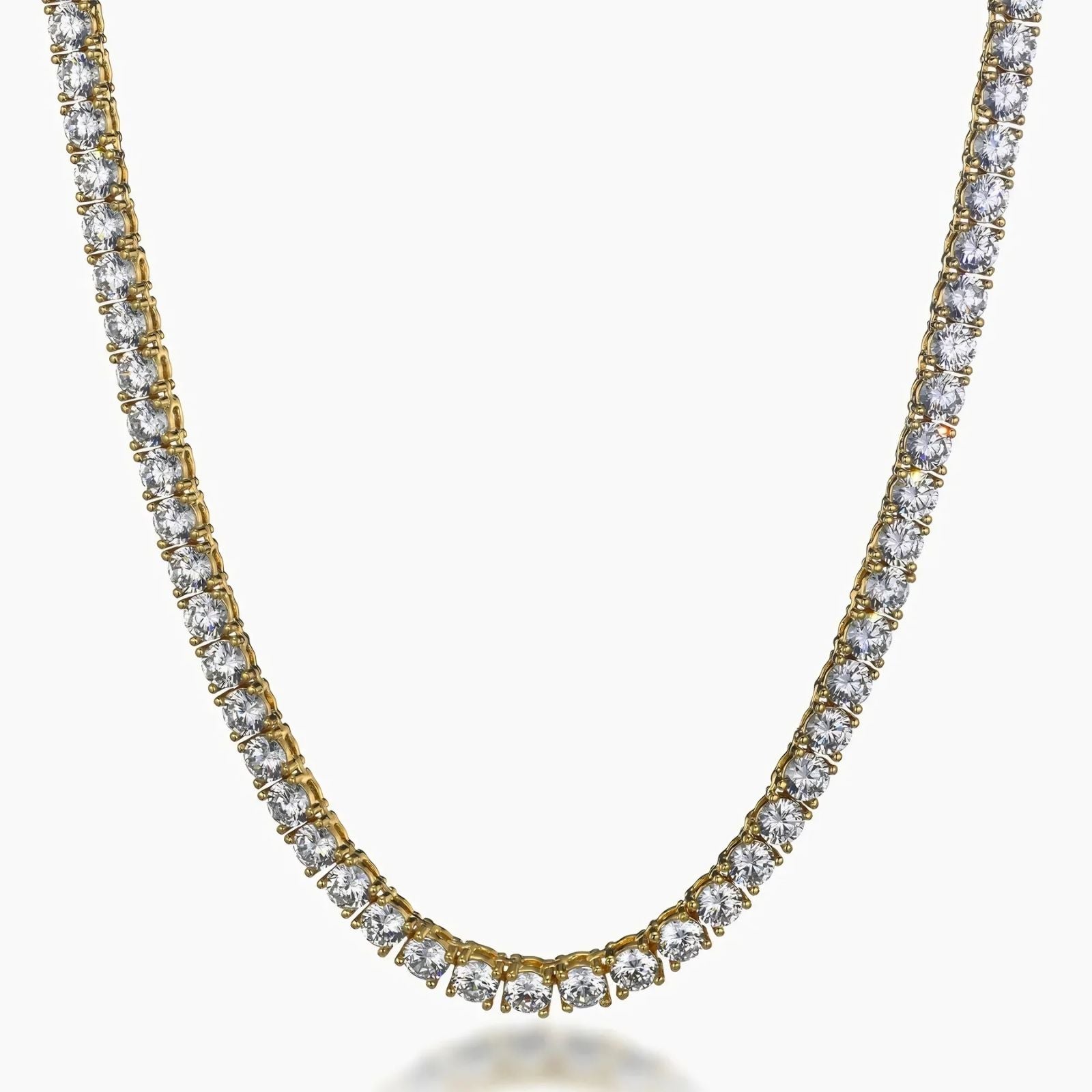 A gold tennis necklace with clear round-cut cubic zirconia, shown on a plain light gray background.