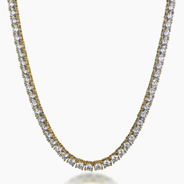 A gold tennis necklace with clear round-cut cubic zirconia, shown on a plain light gray background.
