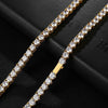 A gold-tone tennis necklace paved with clear round cubic zirconia stones, displayed on a textured black background.
