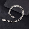 Silver figaro chain bracelet on a dark stone surface