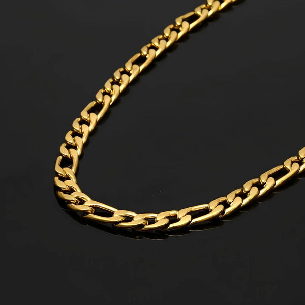 A close-up of a polished gold figaro chain necklace resting on a dark, reflective surface.