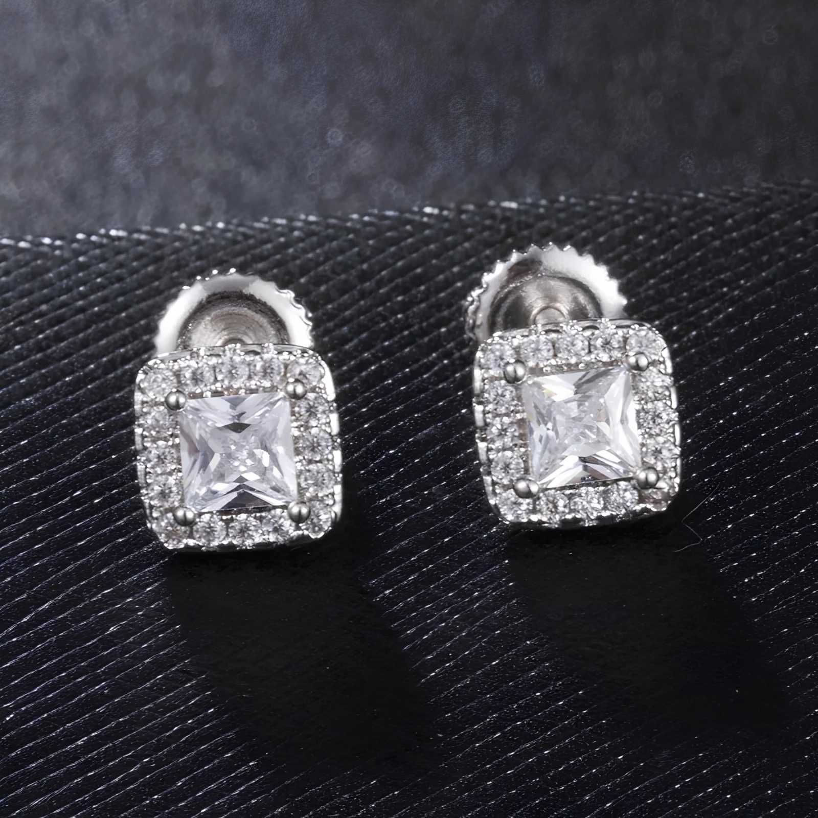 Pair of silver square-shaped earrings with clear cubic zirconia on a black textured background