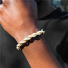 A close-up of a person's wrist wearing a braided rope bracelet in natural beige and off-white tones against a dark background.