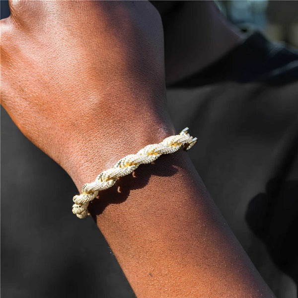 A close-up of a person's wrist wearing a braided rope bracelet in natural beige and off-white tones against a dark background.