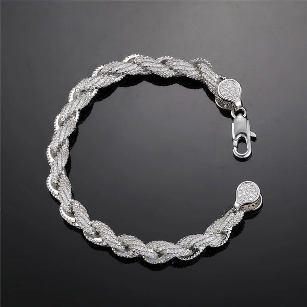 A silver-toned braided chain bracelet with pavé-set clear stones, featuring a lobster clasp and matching round end caps, displayed on a dark reflective surface.