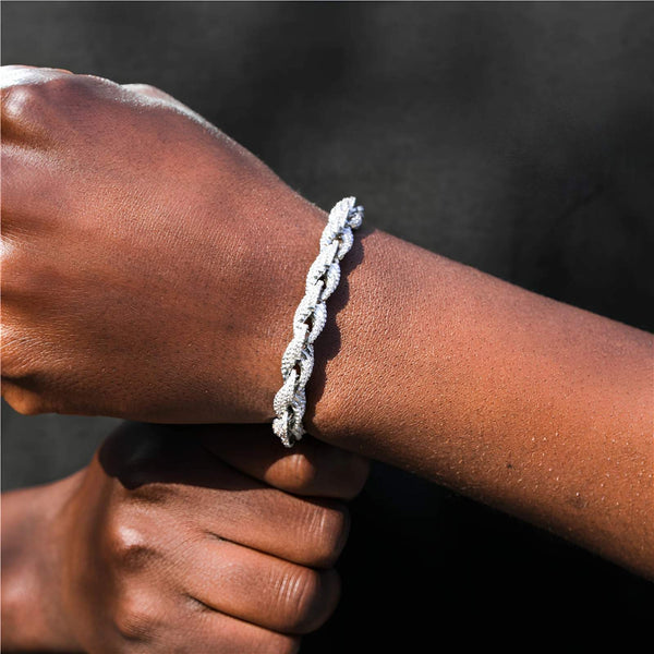 Close-up of a person's wrist wearing a silver braided bracelet against a dark background
