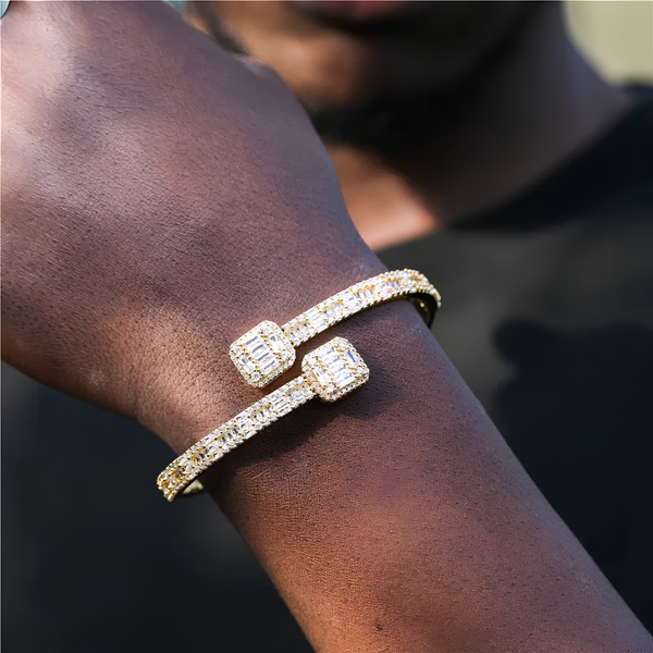 Person wearing a gold baguette cuff bracelet on the wrist.