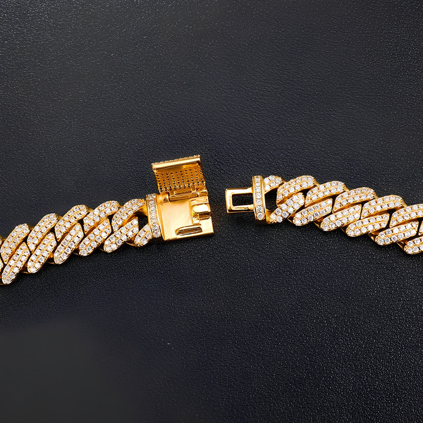 Close-up of the box clasp on a gold iced Cuban bracelet with cubic zirconia stones on a black background.