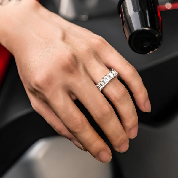 Hand wearing a baguette tennis ring with a blurred background