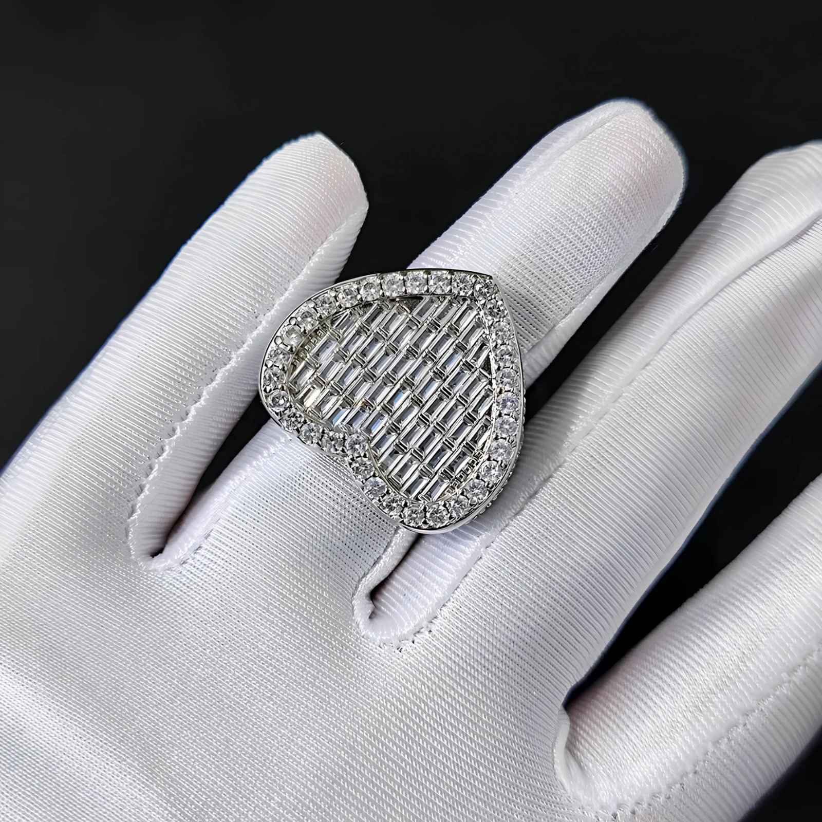 Silver ring with cubic zirconia on a white gloved hand against a black background