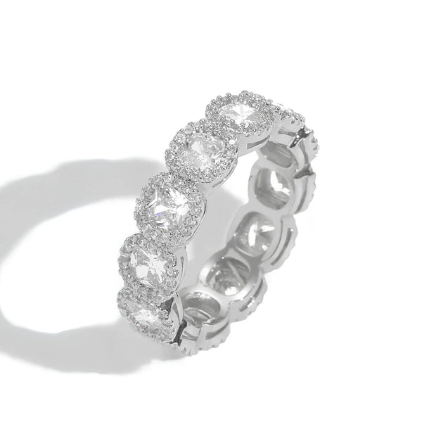 A silver-toned eternity ring featuring a row of round-cut clear cubic zirconia surrounded by small halo accents, photographed on a clean white background with a soft shadow.