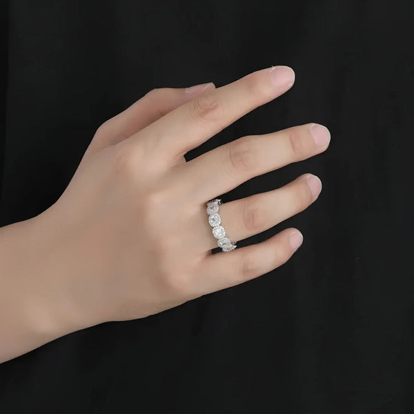 Hand wearing a silver ring with multiple cubic zirconia stones on a black background