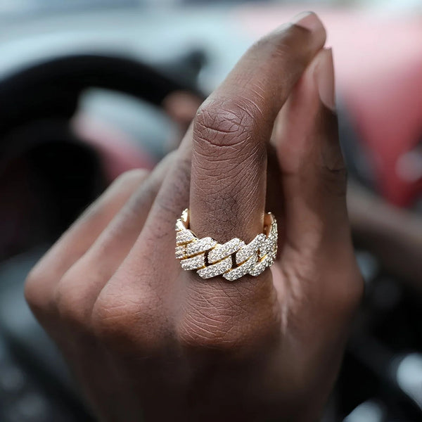Hand wearing a gold ring with cubic zirconia stones with a blurred background
