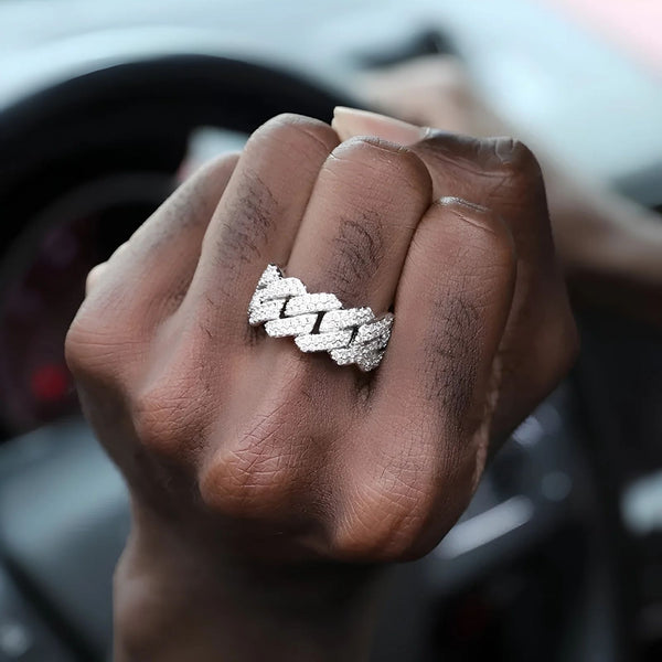 Hand wearing a cubic zirconia cuban ring with a blurred car interior background
