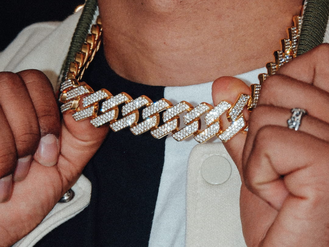 Close-up of hands wearing an iced gold Cuban chain and matching jewellery by Lourdane.