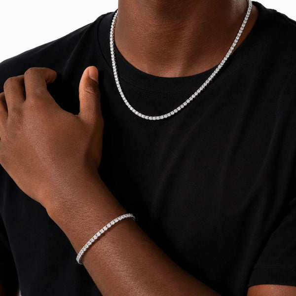 Person wearing a tennis necklace and bracelet on a black background