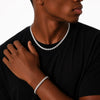 Person wearing a tennis necklace and bracelet on a black background