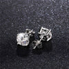 Silver stud earrings with a clear moissanite stone on a black textured background