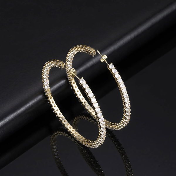 Angled view of gold eternity hoop earrings on black background