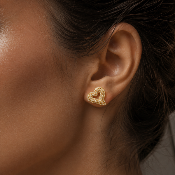 Gold pavé heart stud earrings worn on ear
